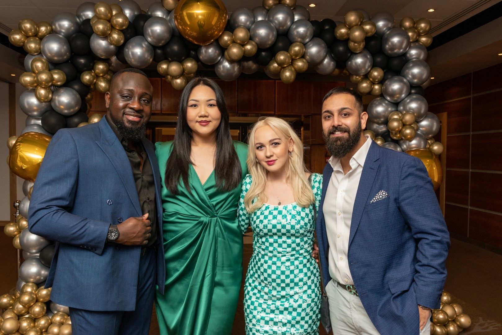 Attendees of the General Practice Awards 2023 wearing green and navy evening wear, surrounded by a gold and silver balloon arch